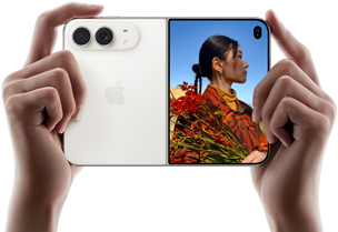 iPhone Duo, warna Putih Star White, dipegang dengan dua tangan dalam orientasi horizontal, tidak dilipat, panel kiri menampilkan kamera belakang Dual Fusion 48 MP, panel kanan menampilkan seseorang yang sedang difoto di layar luar, subjek foto dapat melihat wajahnya saat difoto menggunakan Duo Preview